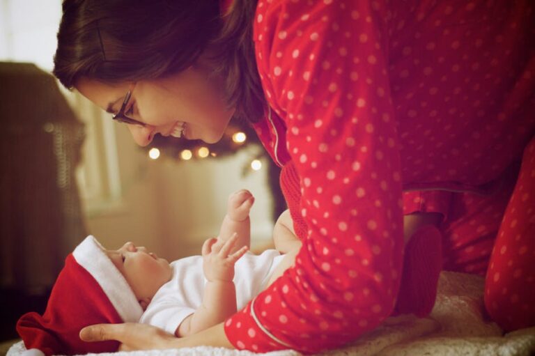 A joyful moment captured as a mother and baby in red pajamas enjoy their first Christmas indoors.